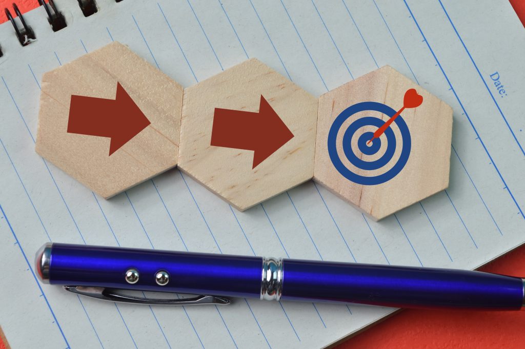 Pen and wooden hexagon with arrows and target symbols. Business strategy and action plan concept